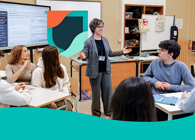 Teacher speaking to students in a classroom with digital learning tools.