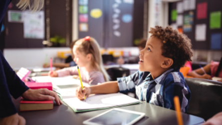 Teacher guiding child in classroom.